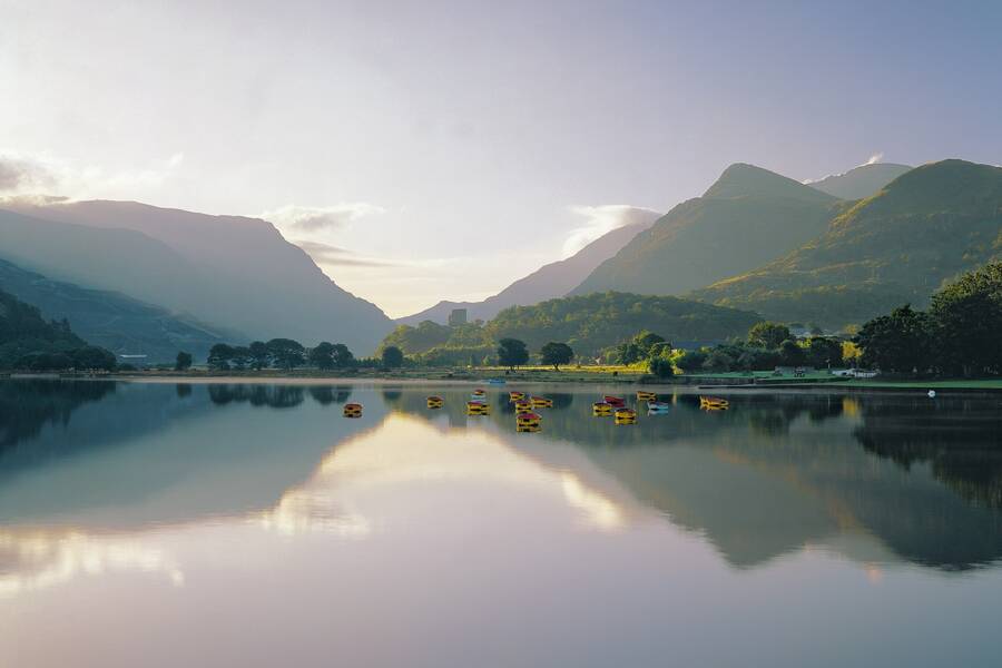 Calm reflections on Llyn Padarn with surrounding mountains and trees at Llanberis.